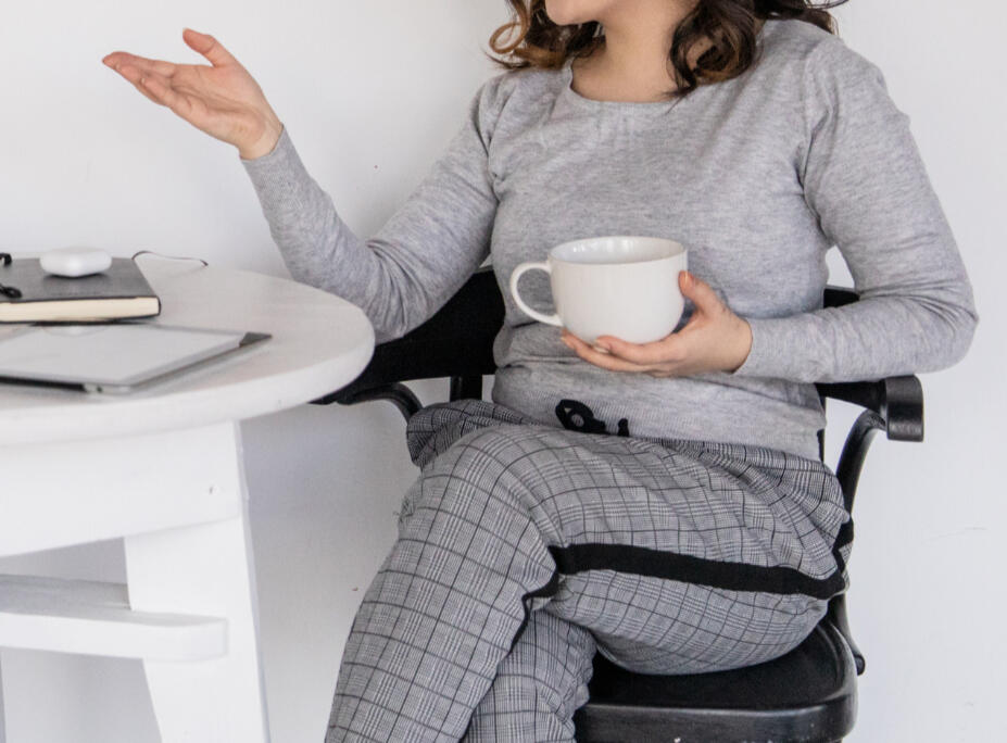 Woman sitting at a table holding a coffee mug, engaged in an individual therapy session in a cozy home setting